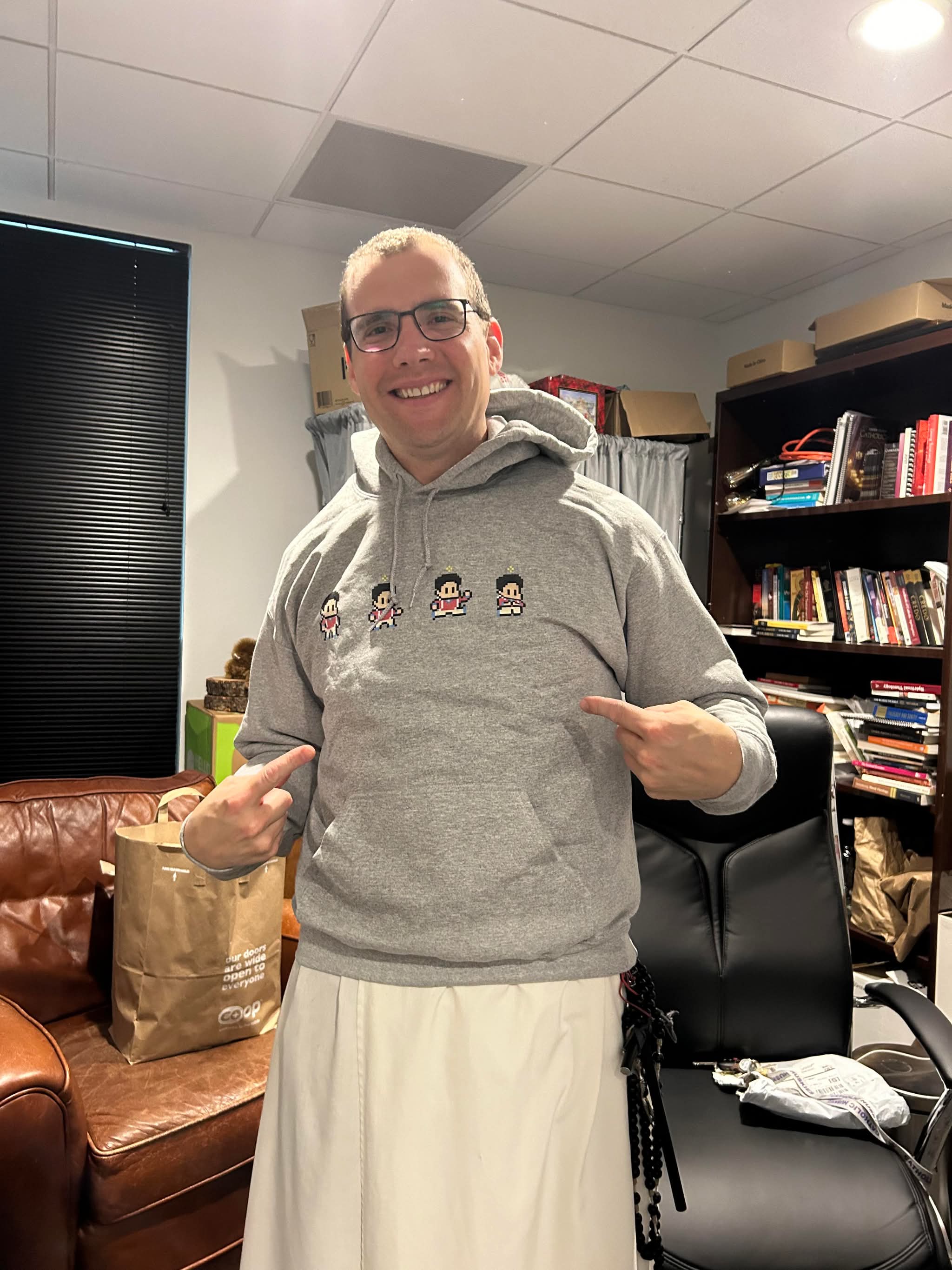 Dominican priest wearing a gray Saint Sprites Carlo hoodie
